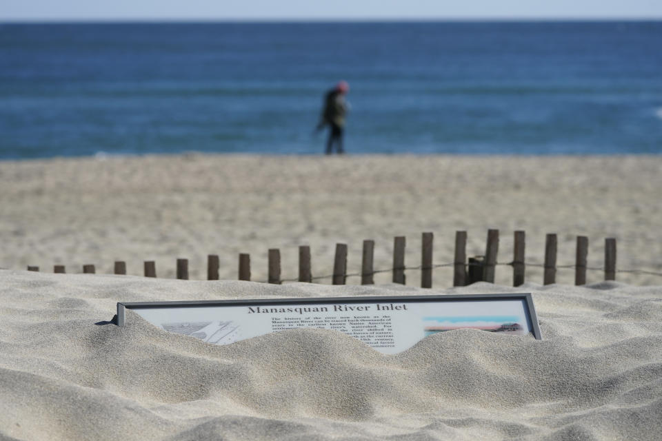 Sand covers a sign on the beach near the Manasquan Inlet in Manasquan, N.J., Thursday, Oct. 20, 2022. After Superstorm Sandy struck the northeast U.S. in 2012, an unprecedented effort began to fortify the densely populated coastline against the next big storm. Then, last year, the region learned that even all those precautions might not be enough in an age of more powerful storms.(AP Photo/Seth Wenig)