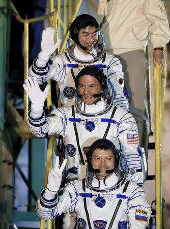 The International Space Station (ISS) crew members Kjell Lindgren of the U.S. (C), Oleg Kononenko of Russia (bottom) and Kimiya Yui of Japan wave as they board the Soyuz TMA-17M spacecraft at the Baikonur cosmodrome, Kazakhstan, July 23, 2015. REUTERS/Yuri Kochetkov/Pool