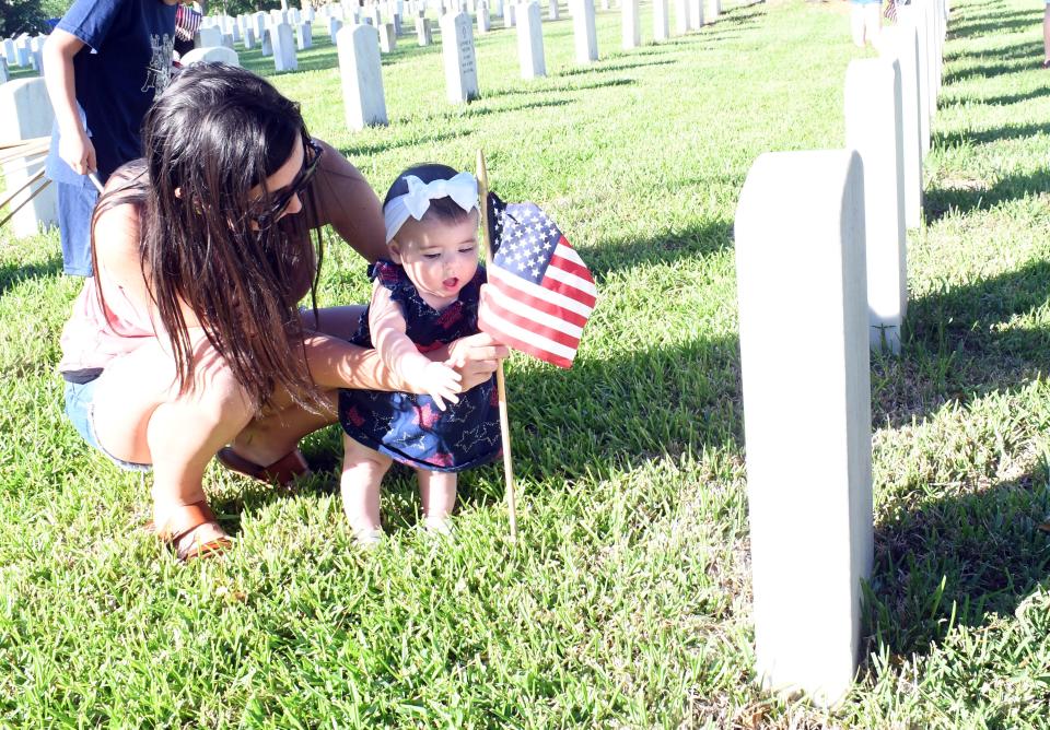 Kaylie Green and Taylor Green place flags on gravesites in preparation for the Memorial Day program set for Monday.