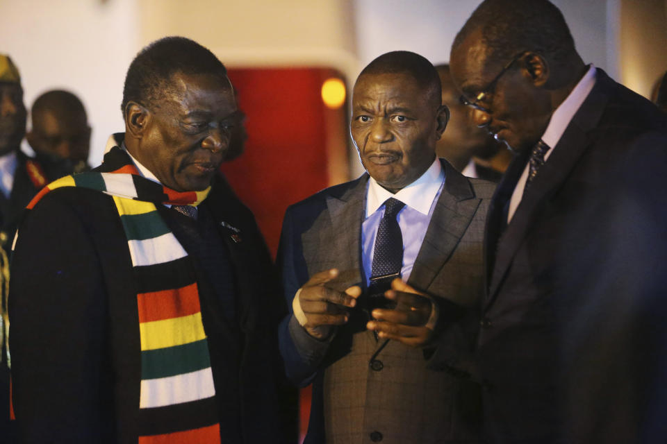 Zimbabwean President Emmerson Mnangagwa, left, arrives at Robert Mugabe International Airport in Harare, Zimbabwe, Monday, Jan. 21, 2019. Mnangagwa arrived in Harare late Monday after cutting short his fund-raising trip in order to address the country's economic crisis and crackdown. (AP Photo/Tsvangirayi Mukwazhi)