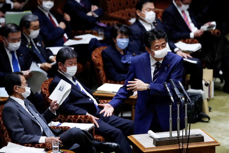 FILE PHOTO: Japan's Prime Minister Shinzo Abe wearing a protective face mask gestures next to Japan's Finance Minister Taro Aso during an upper house parliamentary session in Tokyo