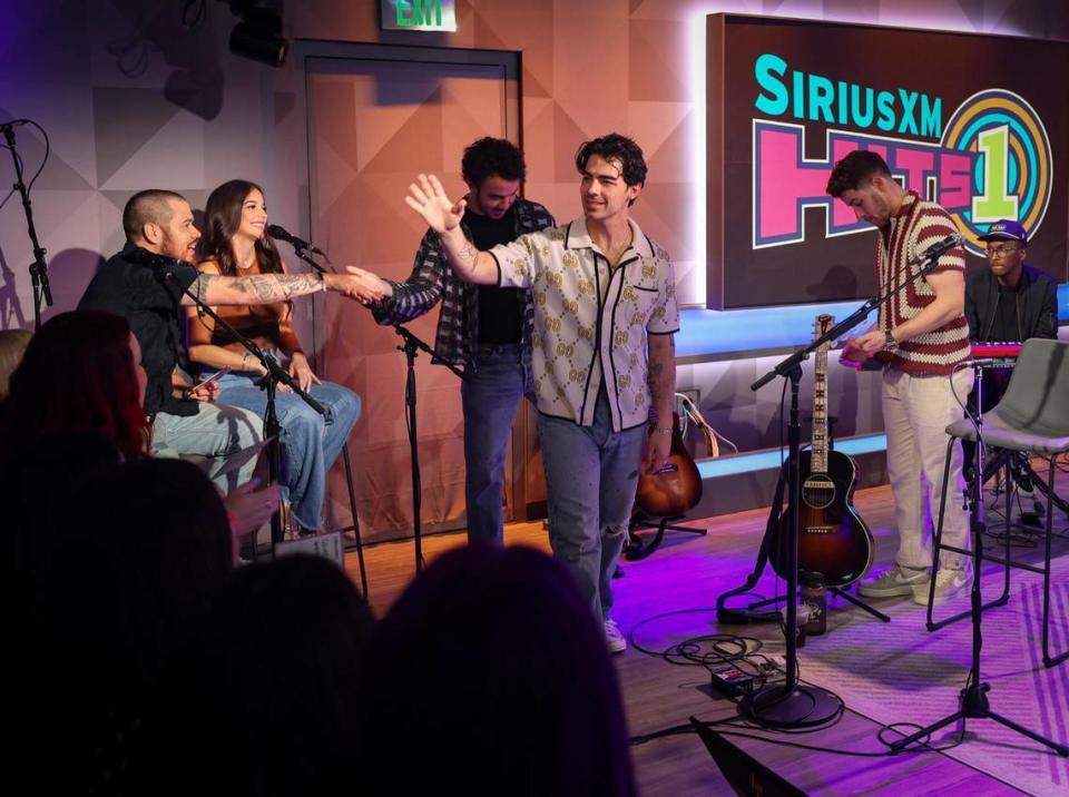 Joe Jonas, center, waves to a room full of about 30 fans that came to see him and his brother, the Jonas Brothers, perform live during SiriusXM’s opening week of their new studio on Friday, May 5, 2023, in Miami Beach.