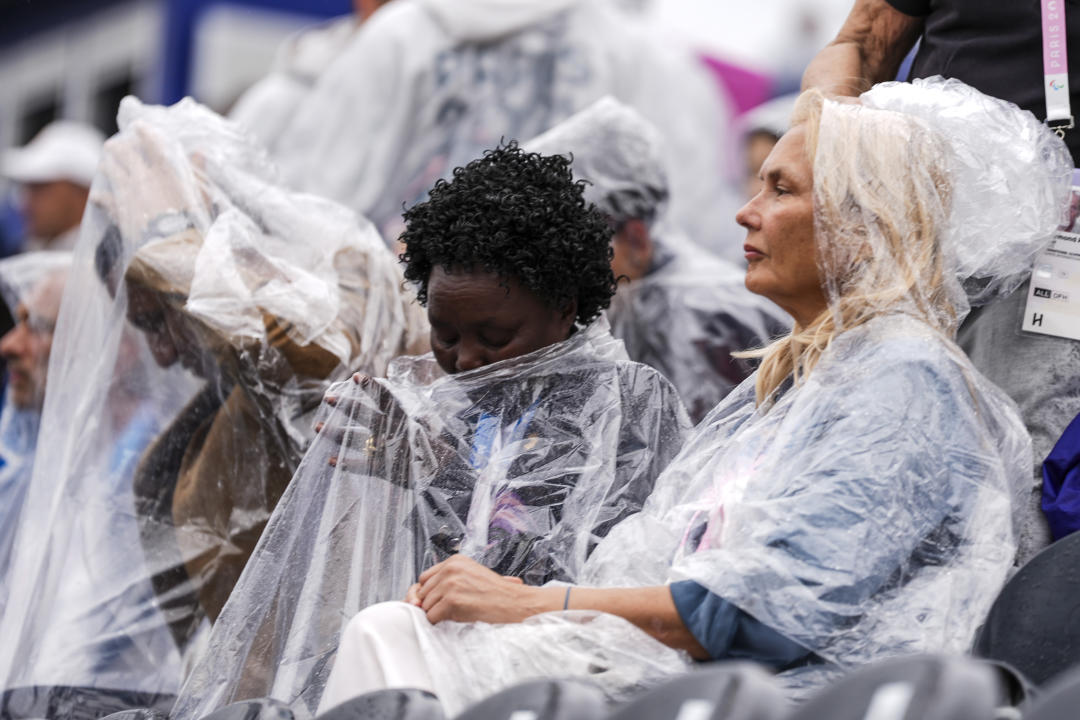 PARIS, FRANCE - JULY 26: Spectators waiting to watch the opening ceremony of the 2024 Paris Olympics try to shield themselves from the rain in Paris, France on July 26, 2024. (Photo by Mustafa Ciftci/Anadolu via Getty Images)