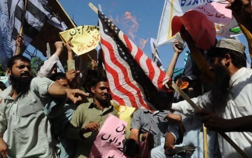 Pakistani demonstrators burn an US flag during an anti-Islam film protest rally in Lahore. Pakistan distanced itself Sunday from a cabinet minister's bounty for killing the maker of anti-Islam film "Innocence of Muslims", as protests against the movie continued from Turkey to Hong Kong