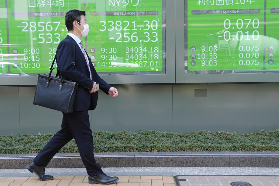 A man walks by an electronic stock board of a securities firm in Tokyo, Wednesday, April 21, 2021. Shares skidded in Asia on Wednesday after Wall Street closed lower for a second straight day, led by drops in technology companies and banks. (AP Photo/Koji Sasahara)