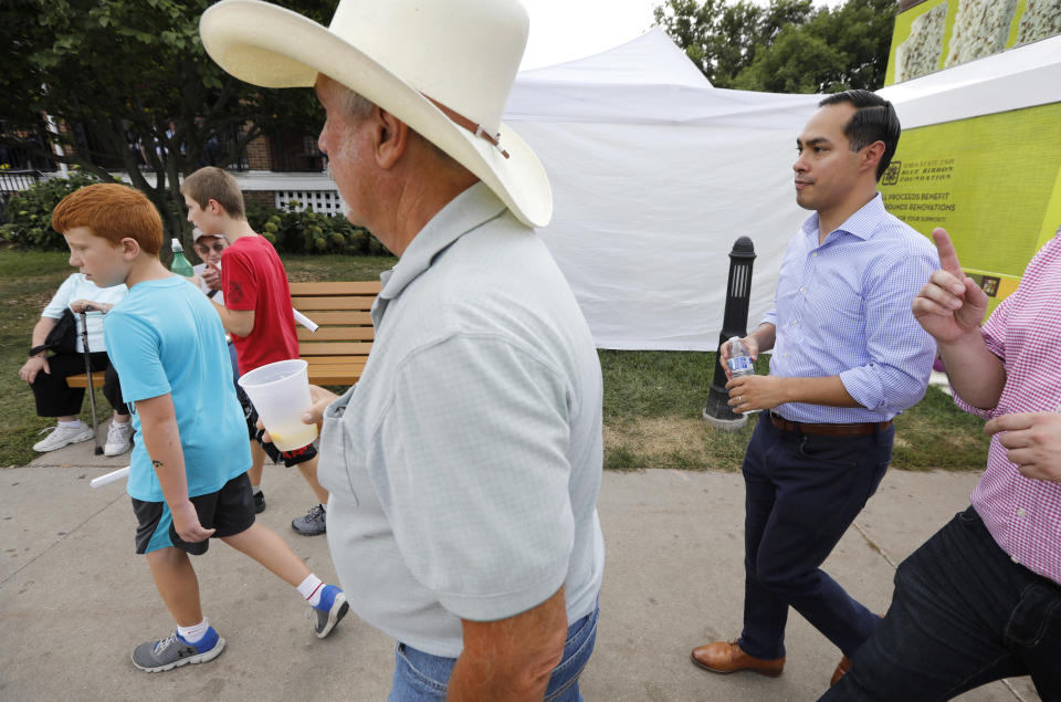 FILE - In this Aug. 17, 2018 file photo, former Housing and Urban Development Secretary Julian Castro, right, walks down the main concourse during a visit to the Iowa State Fair in Des Moines, Iowa. Castro, a Democrat, says he'll "likely" seek the presidency in 2020 after months of signs that former President Barack Obama's housing secretary is preparing for a White House run. Castro told The Associated Press on Tuesday, Oct. 16, 2018, that the Democratic nomination is a wide-open race and says voters are open to considering new faces.(AP Photo/Charlie Neibergall File)