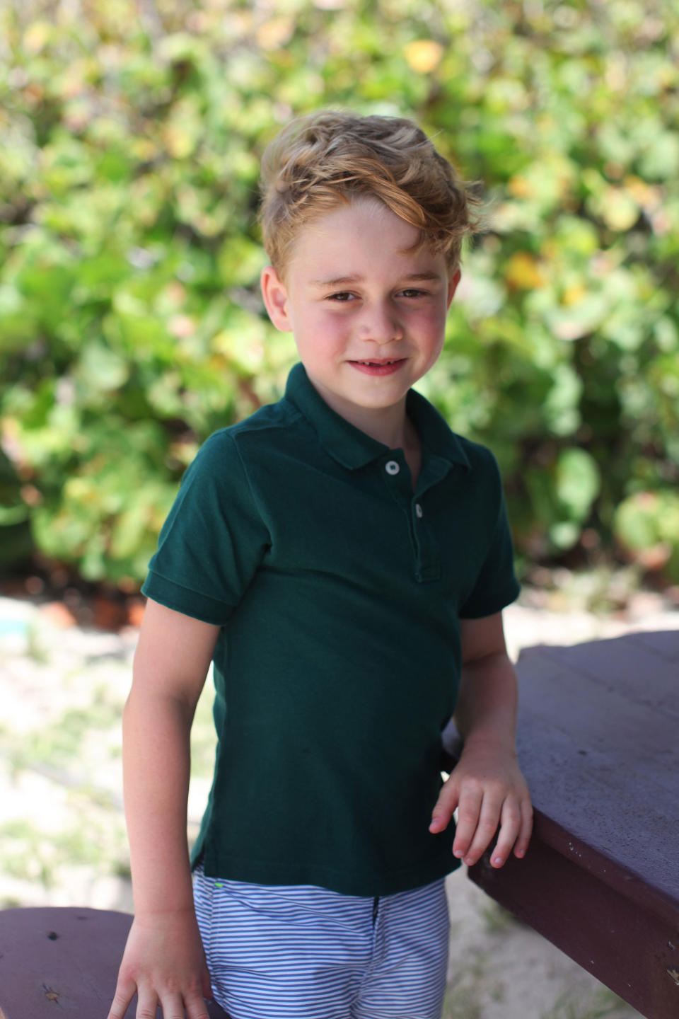 Prince George smiles wearing a green shirt 