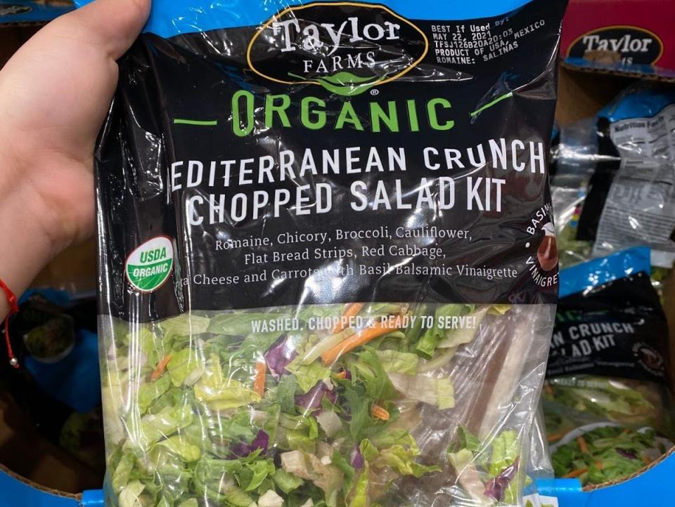 hand holding a bag of costco's organic mediterranean salad mix