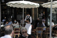 People sit on the Cafe de Flore terrace in Paris, Tuesday, June 2, 2020. Parisians who have been cooped up for months with take-out food and coffee will be able to savor their steaks tartare in the fresh air and cobbled streets of the City of Light once more, albeit in smaller numbers. (AP Photo/Christophe Ena)