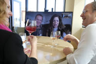 Don Overly and his wife Mardel take part in a live virtual wine tasting from their home near Reno, Nev., with Bouchaine Vineyards winemaker and general manager Chris Kajani, left, and sales director Brian Allard Thursday, March 19, 2020, in Napa, Calif. The winery is presently closed to visitors because of the coronavirus threat, but just started conducting tastings to its customers online. People wanting to taste can select from three different wine tasting kits. The wine included in the kit is shipped to the recipient with instructions on booking an appointment and how to access the virtual contact via the internet. (AP Photo/Eric Risberg)