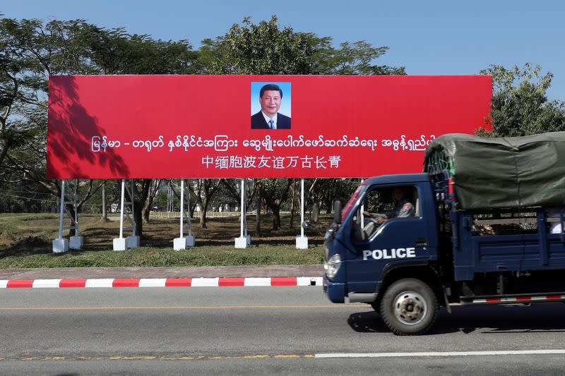 A police van drives by a banner welcoming Chinese President Xi Jinping ahead of his visit to Myanmar in Naypyitaw