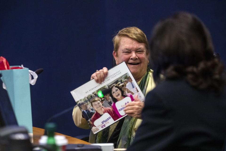 Kuehl, 81, holds up a book and smiles