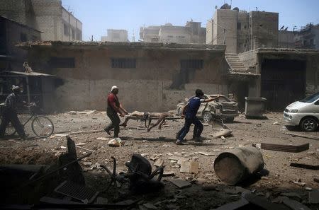 Men transport a casualty at a site hit by airstrikes in the rebel held Douma neighbourhood of Damascus, Syria, July 25, 2016. REUTERS/Bassam Khabieh