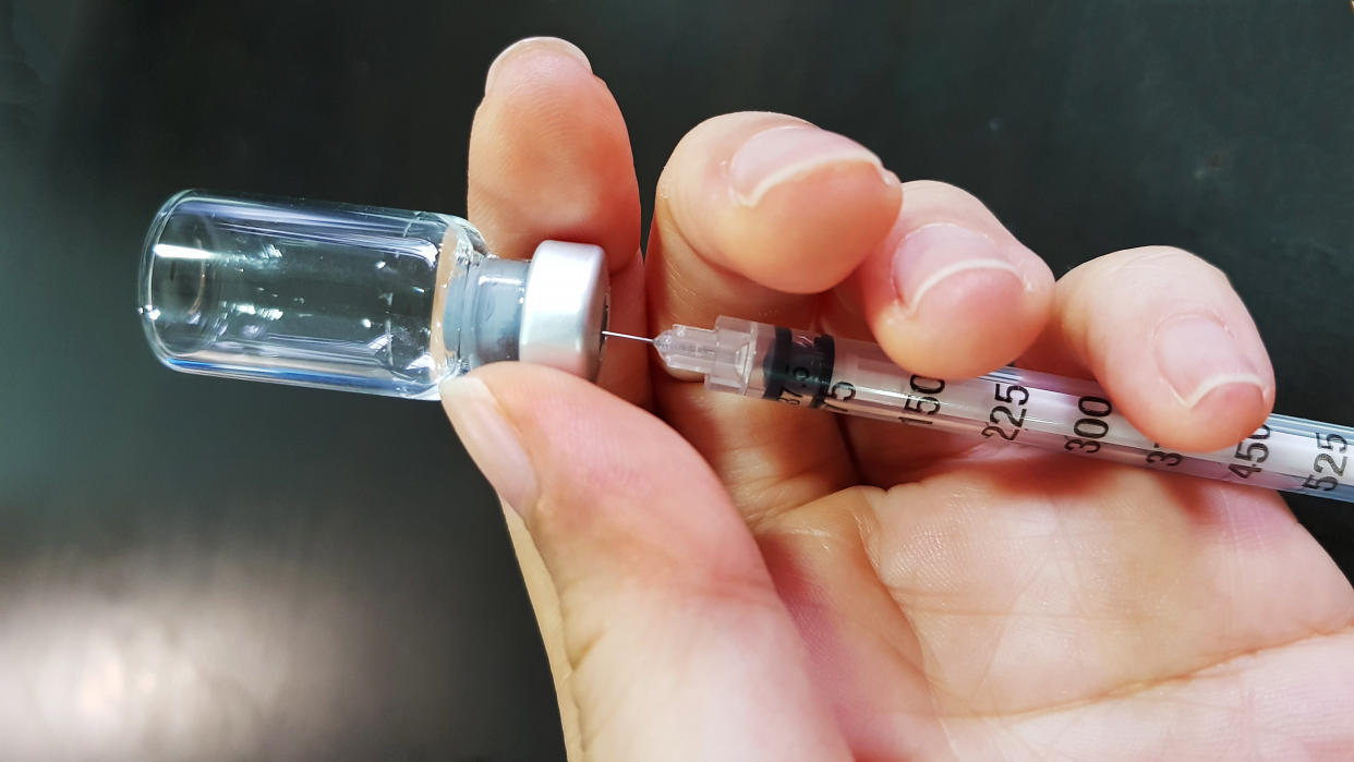 Close up of hand drawing out vaccine liquid from a vial
