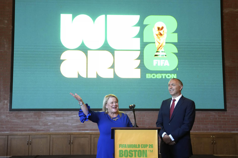 Martha J. Sheridan, President and CEO, Meet Boston, left, and Brian Bilello, President of Boston Soccer 2026, and the New England Revolution, right, stand in front of a projection of a logo as part of Boston Soccer 2026's local branding for the 2026 World Cup, during ceremonies, Thursday, May 18, 2023, in Boston. Gillette Stadium in Foxborough, Mass., is one of 16 venues in the United States, Mexico and Canada tapped to host soccer matches for the international sporting event. (AP Photo/Steven Senne)