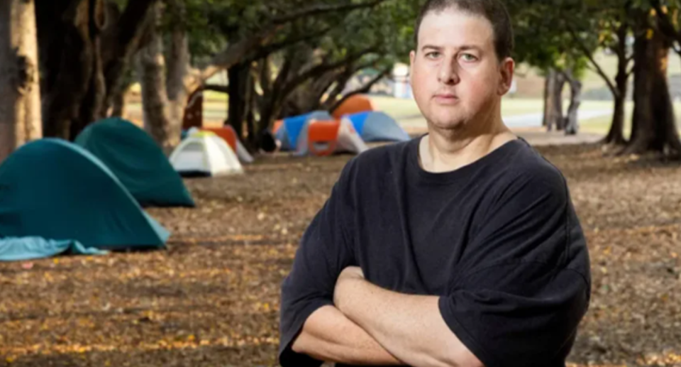 Paul Slater pictured in front of a row of tents. He founded Northwest Community Group which helps people experiencing homelessness across Brisbane.