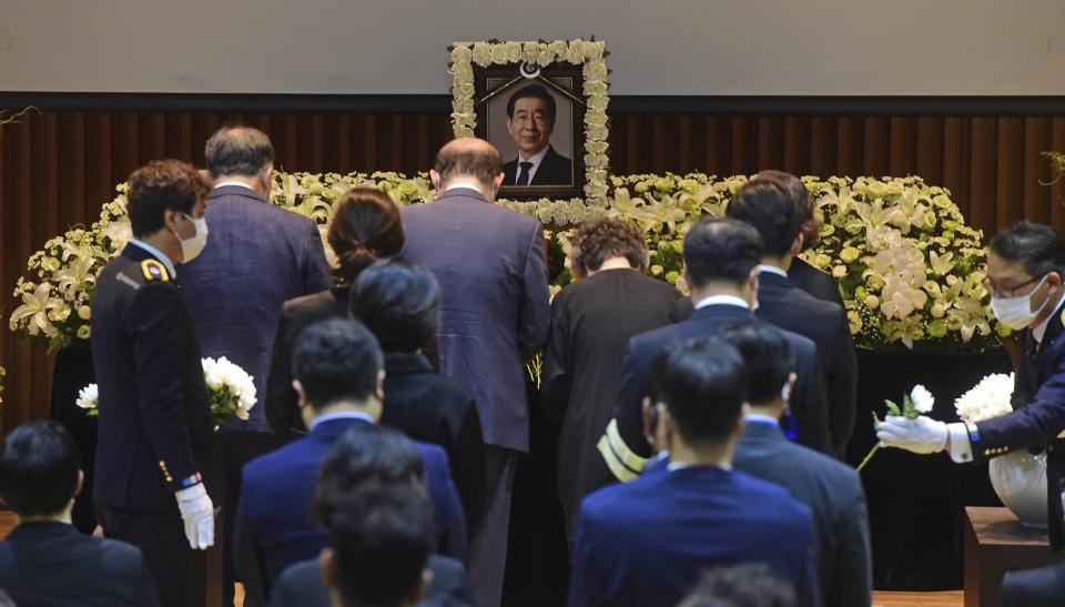 Bereaved family members place flowers to pay respects during an official funeral of late Seoul Mayor Park Won-soon at the Seoul City Hall in Seoul, South Korea, Monday, July 13, 2020. The online funeral for late Seoul Mayor Park has occurred, with a stream of condolence messages posted on YouTube channels which broadcast the event live. Authorities allowed only about 100 people to attend Park Won-soon’s funeral inside the Seoul City Hall on Monday and asked others to watch it online citing coronavirus concerns.(Korea Pool/Yonhap via AP)