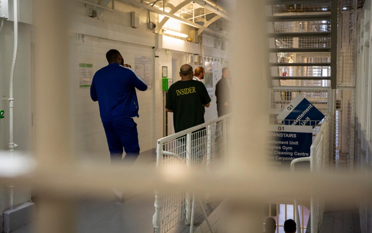 Two male prisoners walk down the landing towards to Prison Officers in G Wing Level 2 of Her Majestys Prison Pentonville