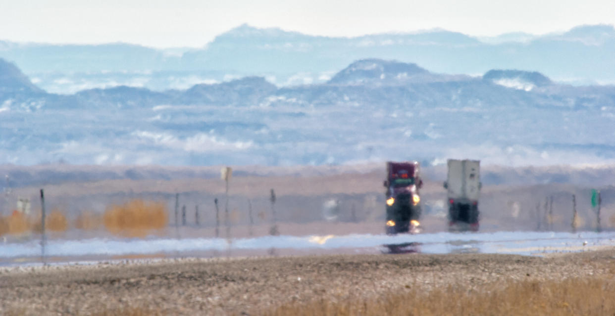 Heat Haze Distorts Video of Semi-Trucks Driving Down a Utah Interstate Surrounded by Mountains on a Sunny Day