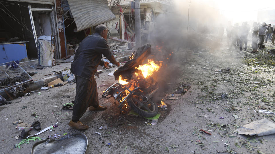 A man tries to put out a fire after a car bomb exploded in Tal Abyad, Syria, Friday, Nov. 2, 2019. A car bomb exploded in a northern Syrian town along the border with Turkey Saturday killing over a dozen of people, Turkey's defense ministry said. (AP Photo)