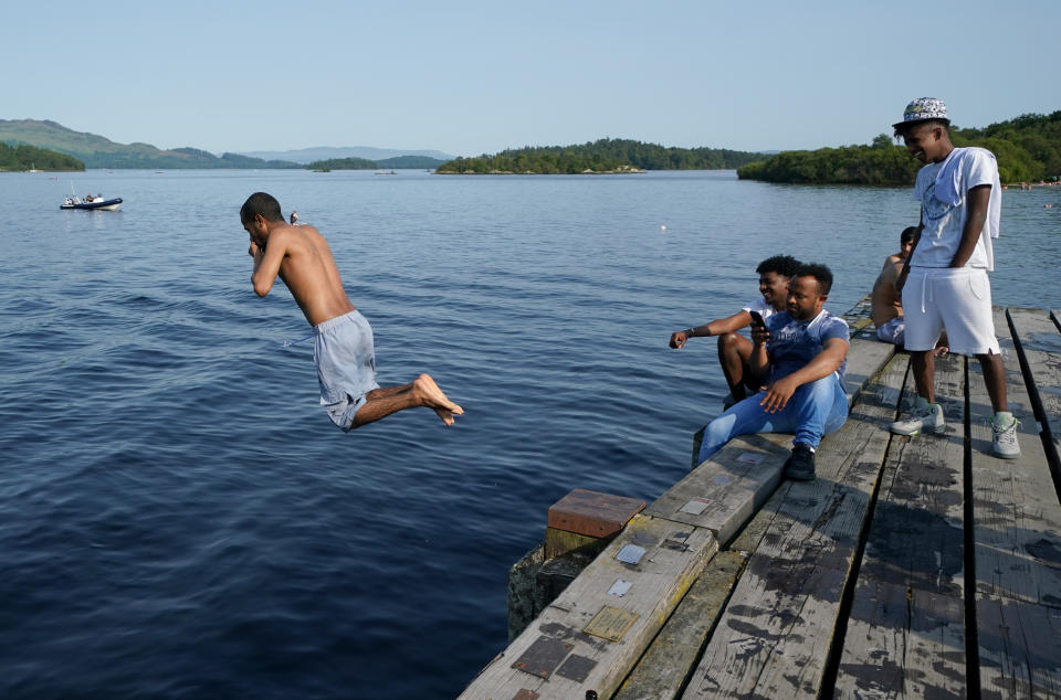 People jump from a pier into the water of Loch Lomond, in the village of Luss in Argyll and Bute, Scotland. Picture date: Monday July 18, 2022.