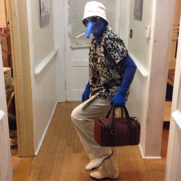 A man dressed as Gonzo from "The Muppets" while holding a weekend bag