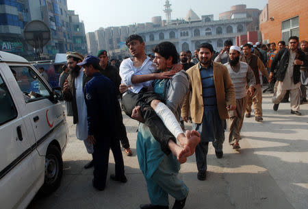 A man carries a student, who was injured during an attack by Taliban gunmen on the Army Public School, after he received treatment at a hospital in Peshawar, December 16, 2014. REUTERS/Khuram Parvez