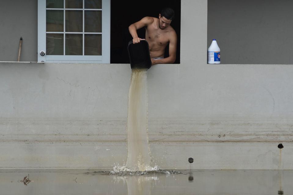 A resident bails water from a flooded home in the aftermath of Hurricane Maria, in Catano, Puerto Rico, Wednesday, Sept. 27, 2017. But the scope of the devastation from Hurricane Maria is so broad, and the relief effort so concentrated in San Juan, that many people from outside the capital say they have received little to no help.
