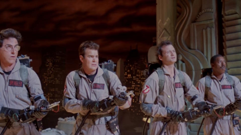 The Ghostbusters stand on a smoky rooftop in New York