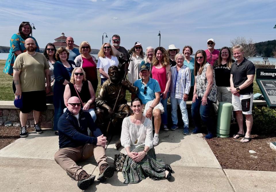 Attendees at the 2023 Writer’s Retreat in Walloon Lake, including the the grandson of Ernest Hemingway, author John Patrick Hemingway, take a photo with the Hemingway statue in downtown Walloon Lake.
