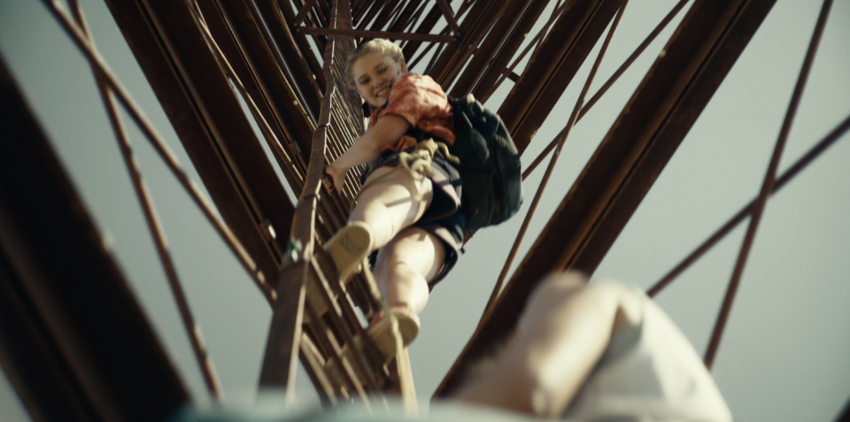 A girl climbing a ladder looks down and smiles