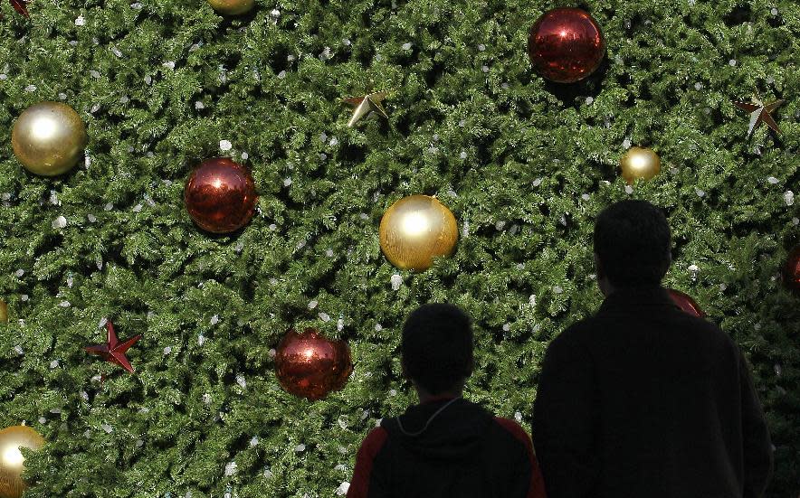 FILE - In this Friday, Nov. 23, 2012, file photo, two Black Friday shoppers walk past a large Christmas Tree at Union Square in San Francisco. A horrific fire that killed 112 people, Saturday, Nov. 24, 2012, at a Bangladesh garment factory owned by Tazreen Fashions Ltd has put the spotlight back on those factory workers and their sometimes treacherous work environment. The factory made clothing for several retailers around the globe including Wal-Mart, Sears and The Walt Disney Co. The companies said they didn't know the vendors were using the factory and according to a report by the Associated Press, holiday shoppers have also buffered themselves from the tragedy. (AP Photo/Jeff Chiu)