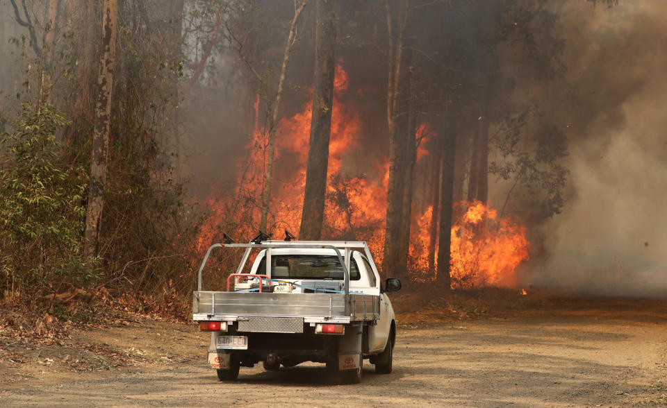 A ute is seen in front of a bushfire burning next to Busby's Flat Road in Busbys Flat, in northern NSW.