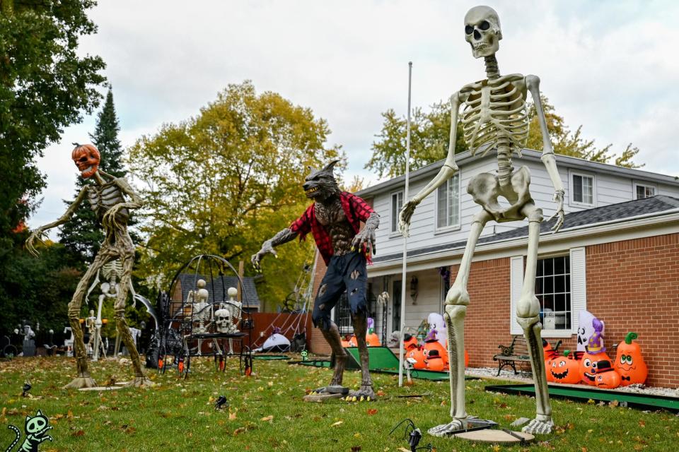 From left, a large pumpkin-headed skeleton, a warewolf and skeleton appear to stand guard at a home at the corner of Wood Street and Groesbeck Boulevard on Wednesday, Oct. 19, 2022, in Lansing.