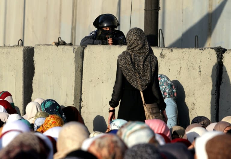 A woman looks at a member of the Israeli security forces standing guard at the Qalandia checkpoint as Palestinians wait to cross from the West Bank to Jerusalem for Friday prayers at the Al-Aqsa Mosque on July 3, 2015