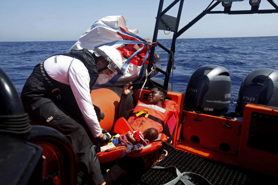 Rescuers from the MV Geo Barents vessel of MSF (Doctors Without Borders) assist a woman and infant, in the Mediterranean Sea, off Libya, in the central Mediterranean route, Monday, Sept. 20, 2021. (AP Photo/Ahmed Hatem)