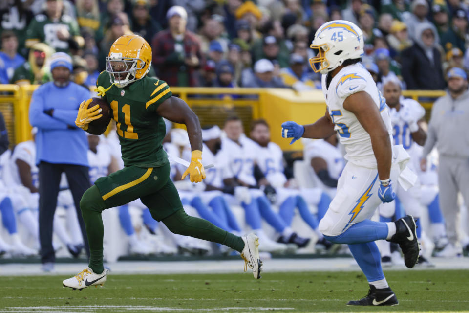 Green Bay Packers wide receiver Jayden Reed (11) runs with the ball on his way to score a touchdown in front of Los Angeles Chargers linebacker Tuli Tuipulotu (45) during the first half of an NFL football game, Sunday, Nov. 19, 2023, in Green Bay, Wis. (AP Photo/Mike Roemer)