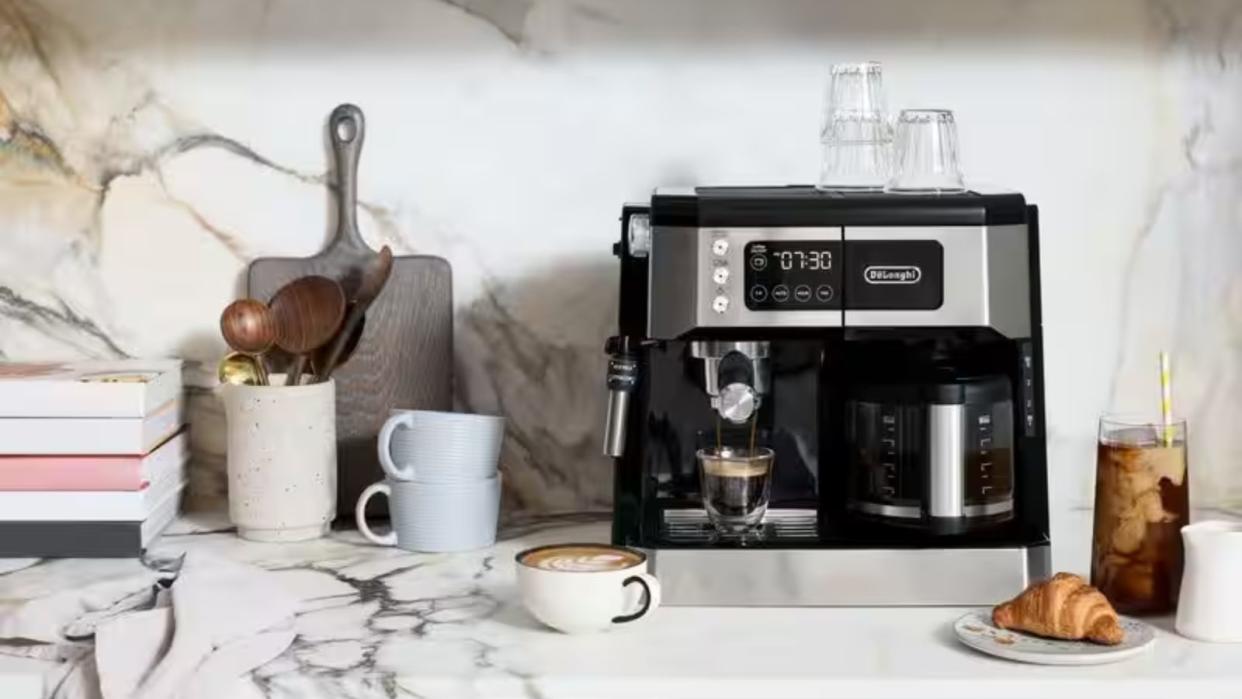  The best espresso machine for beginners: De'Longhi All In One Combination  coffee maker on a marble countertop with coffee mugs, a croissant, and books around it 