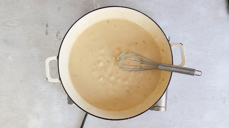 cheese sauce with whisk in pan