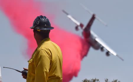 A firefighter watches as a BAe-146 makes a phos-chek drop along the western flank of the Fire near W Camino Cielo while fighting the Whittier Fire near Santa Barbara, California, U.S. July 15, 2017. Mike Eliason/Santa Barbara County Fire Department/Handout via REUTERS