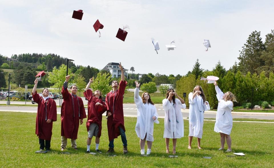 (Left to right) Milo Farnsworth, Kevin Alcazar, Caleb Walker, Logan Gross, Savannah Cronce (Lakeview High School), Barbara Moore, Candice Munson and Sarah Miller toss their caps in the air on Tuesday, June 6.