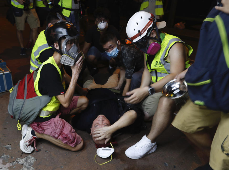 A protester is overcome by tear gas near the Shum Shui Po police station in Hong Kong on Wednesday, Aug. 14, 2019. German Chancellor Angela Merkel is calling for a peaceful solution to the unrest in Hong Kong amid fears China could use force to quell pro-democracy protests.(AP Photo/Vincent Yu)