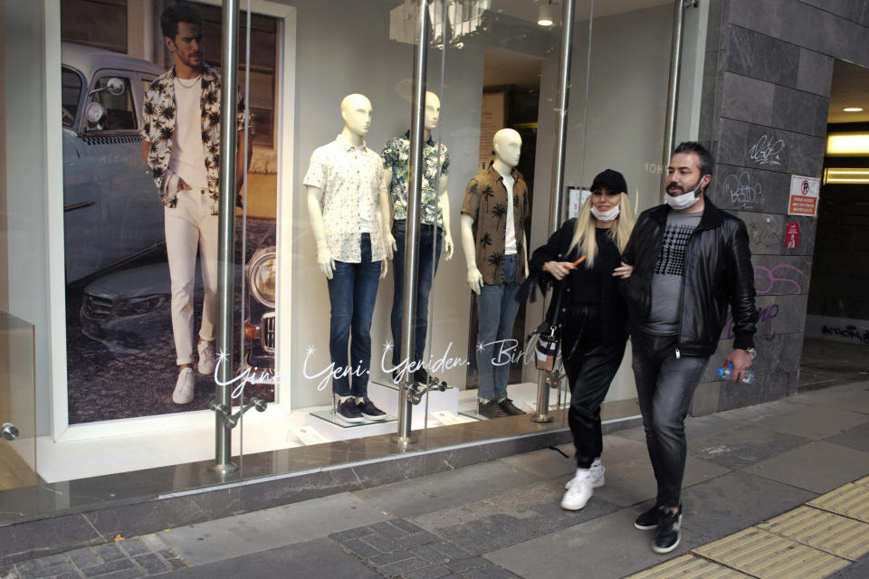 People wearing face masks for protection against the coronavirus, walk in a popular street hours before a two-day new curfew declared by the government in an attempt to control the spread of coronavirus, in Ankara, Turkey, Friday, May 29, 2020. The country has opted to impose short weekend and holiday curfews, instead of full lockdowns, fearing possible negative effects on the already troubled economy.(AP Photo/Burhan Ozbilici)