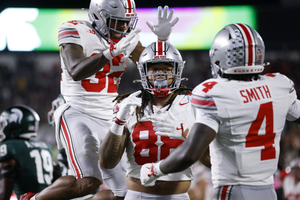 Ohio State tight end Gee Scott Jr., center, Ohio State running back TreVeyon Henderson, left, and Ohio State wide receiver Jeremiah Smith (4) celebrate Scott's touchdown during the first half of an NCAA college football game, Saturday, April 28. September. 2024, in East Lansing, Michigan (AP Photo/Al Goldis)