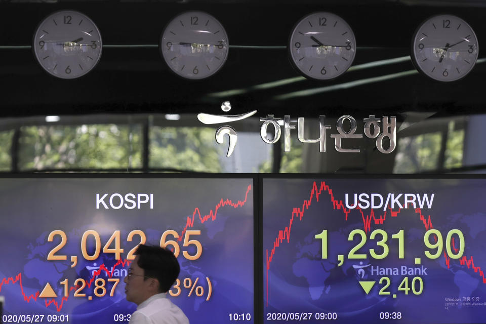 A currency trader walks by the screens showing the Korea Composite Stock Price Index (KOSPI), left, and the foreign exchange rate between U.S. dollar and South Korean won at the foreign exchange dealing room in Seoul, South Korea, Wednesday, May 27, 2020. Major Asian stock markets have declined as US-Chinese tension over Hong Kong competes with optimism about recovery from the coronavirus pandemic. (AP Photo/Lee Jin-man)