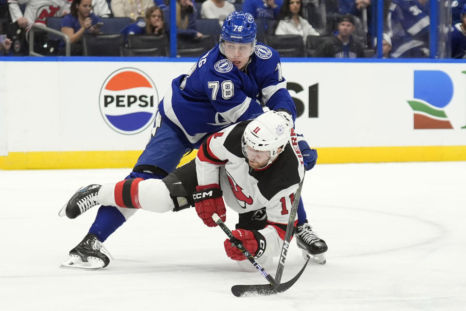 Tampa Bay Lightning defenseman Emil Martinsen Lilleberg (78) knocks down New Jersey Devils center Chris Tierney (11) during the first period of an NHL hockey game Saturday, Jan. 27, 2024, in Tampa, Fla. (AP Photo/Chris O'Meara)