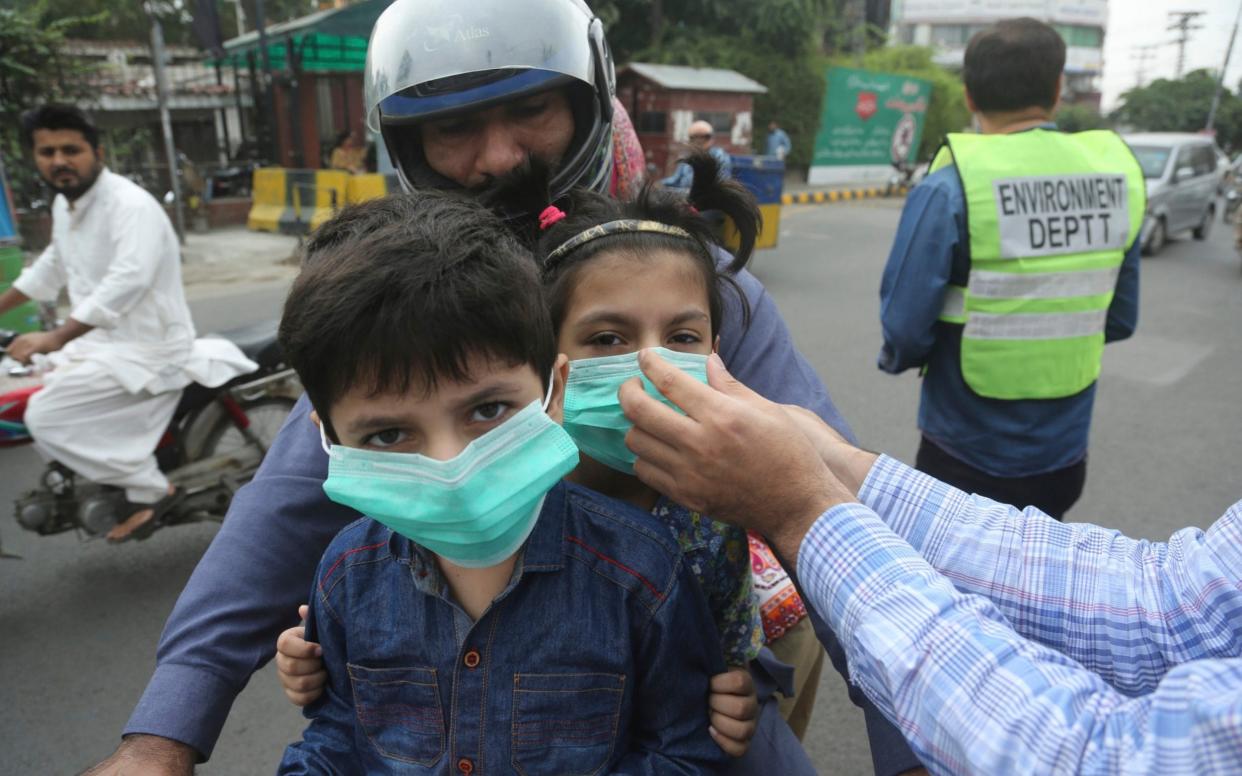 An official hands masks to children in Lahore - AP