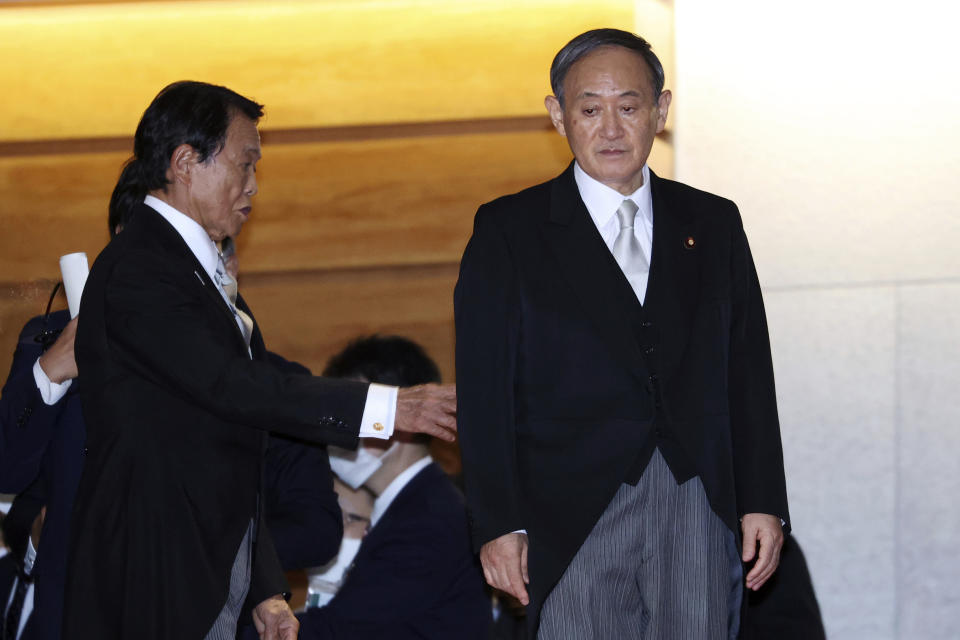 FILE - In this Sept. 16, 2020, file photo, Japanese Prime Minister Yoshihide Suga, right, waits his cabinet members for a photo session after their first cabinet meeting at the prime minister's official residence in Tokyo. Prime Minister Suga's government says it will not look into scandals of a previous government, even though it is largely inheriting former leader's policies. (Yoshikazu Tsuno/Pool Photo via AP, File)