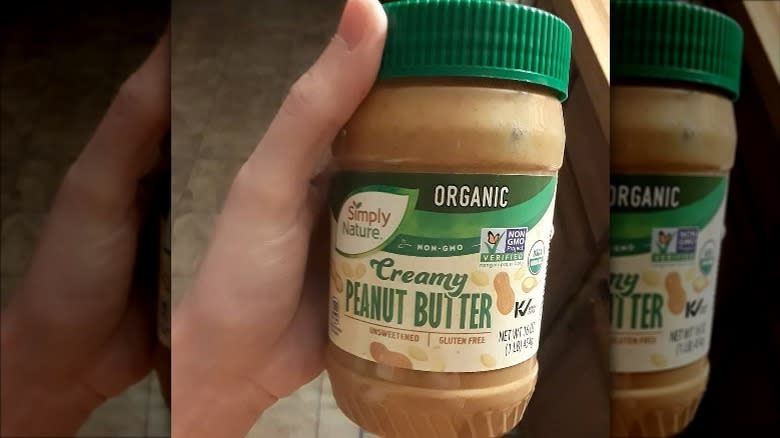 Hand holding Aldi's Simply Nature organic peanut butter