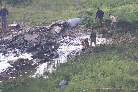 Israeli security forces walk next to the remains of an F-16 Israeli war plane near the Israeli village of Harduf, Israel February 10, 2018. REUTERS/Herzie Shapira